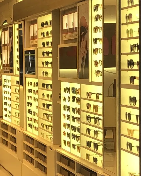 Vitrines iluminadas da loja, com fileiras de armações e óculos de sol nas prateleiras